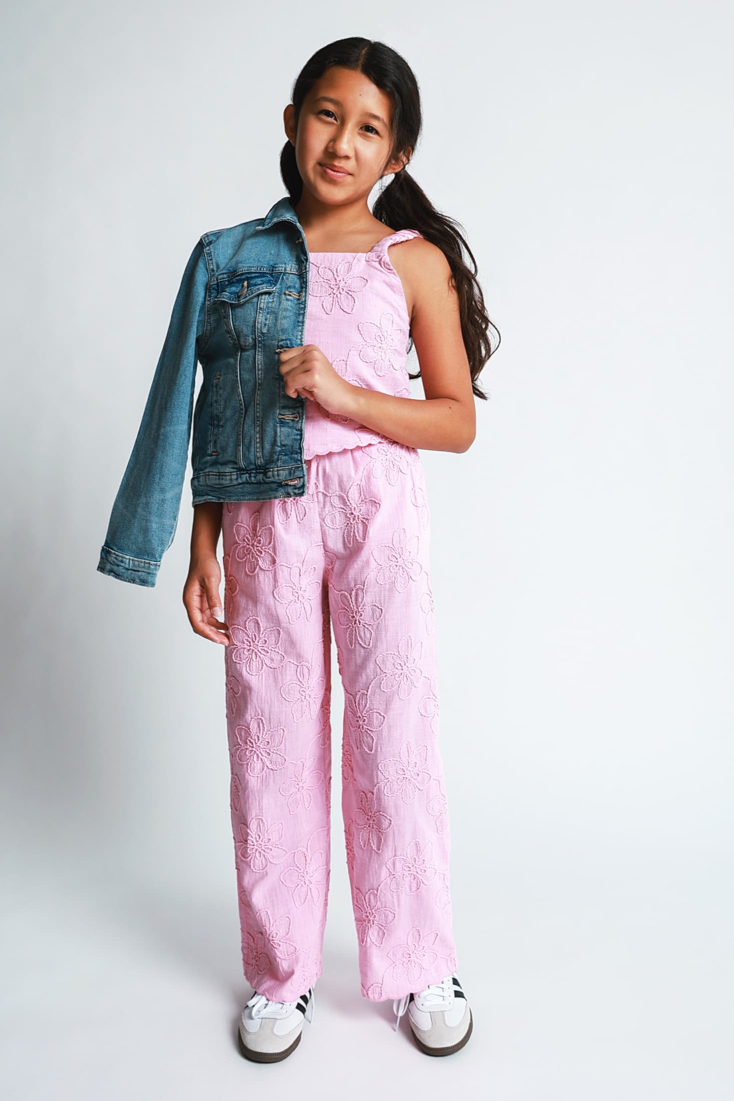 Kylie Akimoto in a pink studio portrait holding a denim jacket